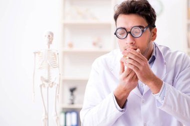 Deli doktor insan iskeletini inceliyor.