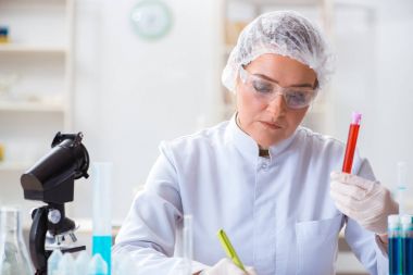 Kadın doktor laboratuvarda kan örneklerini kontrol ediyor.