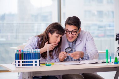 Laboratuvarda deney yapan iki kimyager.