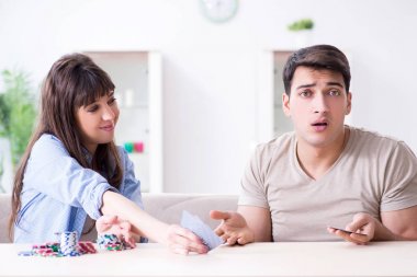 Genç bir aile evde kağıt oynuyor.