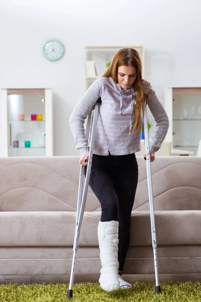 Junge Frau mit gebrochenem Bein zu Hause — Stockfoto