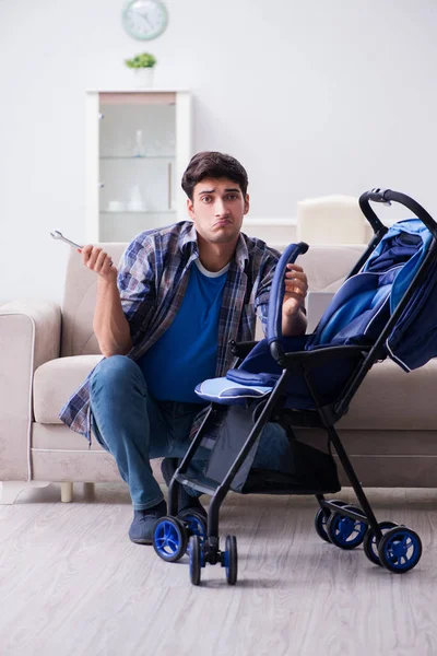 Jeune père assemblant bébé landau à la maison — Photo