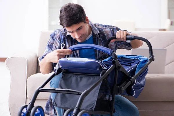 Joven padre montando cochecito de bebé en casa —  Fotos de Stock