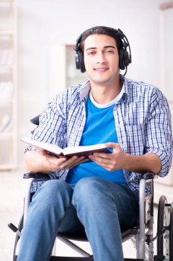 Tekerlekli sandalyede müzik dinleyen engelli adam.