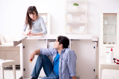 Koca evde kırık masayı onarıyor.