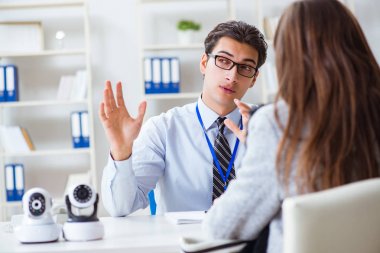 Mağazadaki müşteriye kamera gösteren satış asistanı