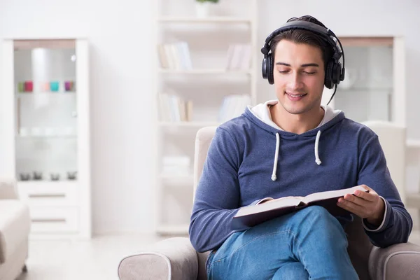 Joven leyendo libro y escuchando audio libro —  Fotos de Stock