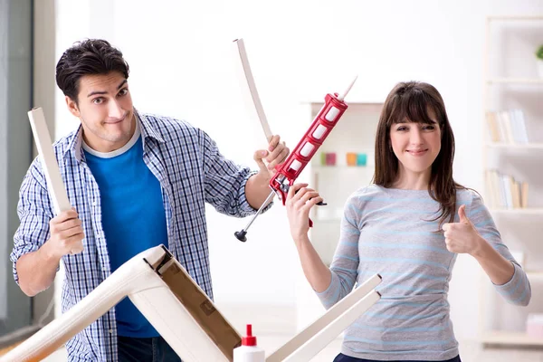 Ehefrau hilft Ehemann, kaputten Stuhl zu Hause zu reparieren — Stockfoto