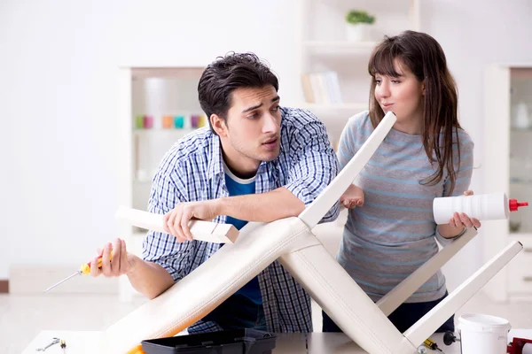 Vrouw helpen man naar reparatie kapotte stoel thuis — Stockfoto