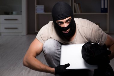 Suç mahallinde kar maskesi takan bir hırsız.