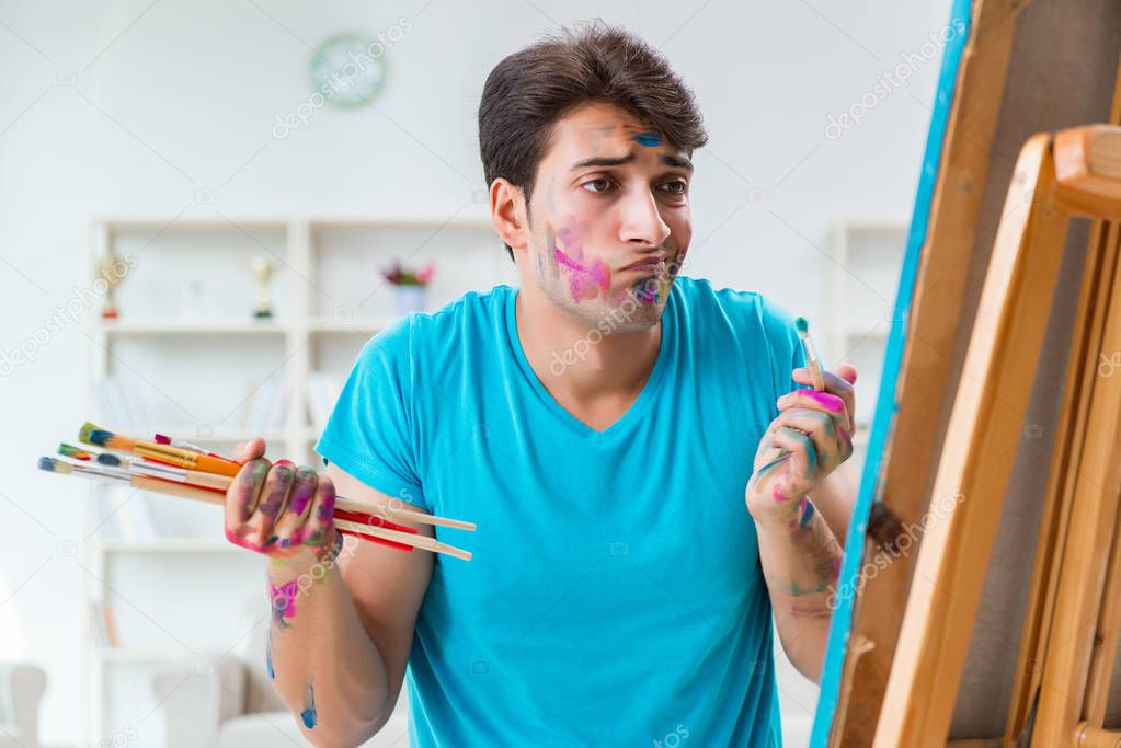 Young funny artist working on new painting in his studio