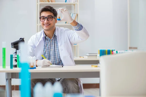 Jovem estudante de química que trabalha em laboratório em produtos químicos — Fotografia de Stock