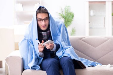 Çalışan işadamı grip olmuşken televizyon izliyor.