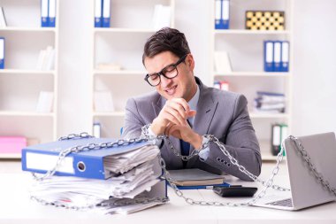 Ofis masasına zincirlenmiş meşgul bir çalışan.