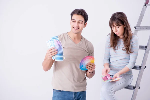 Jovem família fazendo renovação em casa - paredes de pintura — Fotografia de Stock