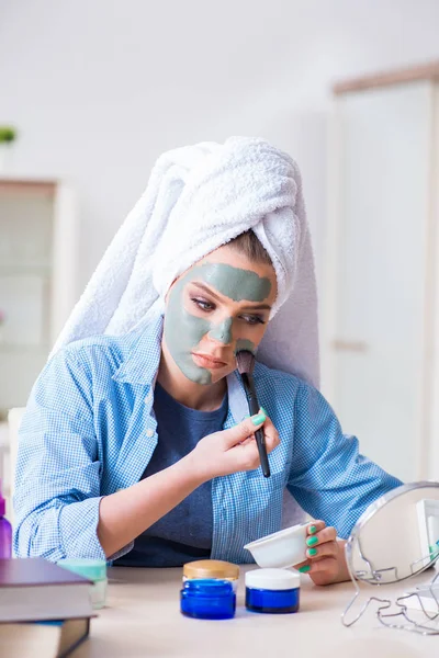 Жінка наносить глиняну маску пензлем в домашніх умовах — стокове фото