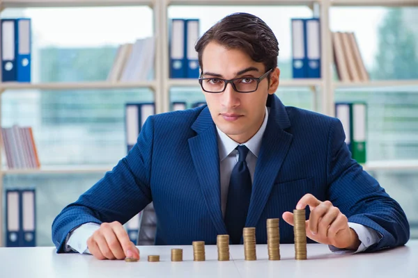 Empresario con pilas de monedas en la oficina — Foto de Stock