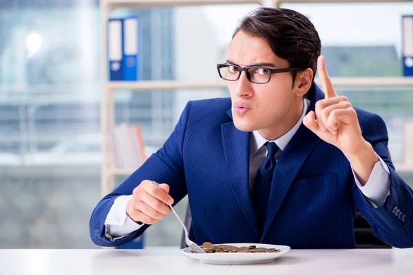 Funny businessman eating gold coins in office