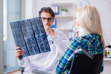 Tekerlekli sandalyedeki engelli kadın erkek doktoru ziyaret ediyor.