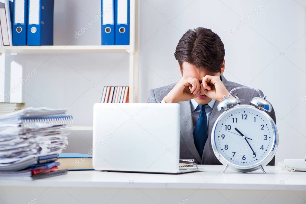 Businessman employee in urgency and deadline concept with alarm clock