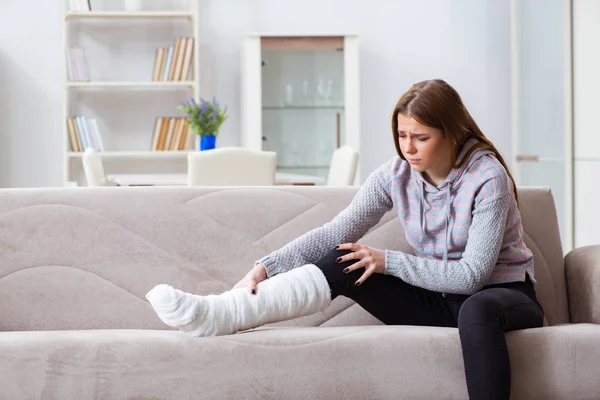 Młoda kobieta ze złamaną nogą w domu — Zdjęcie stockowe