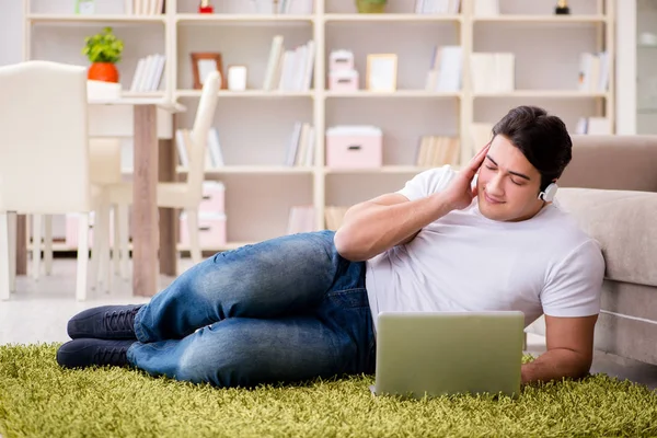 Homem trabalhando no laptop em casa no chão do tapete — Fotografia de Stock