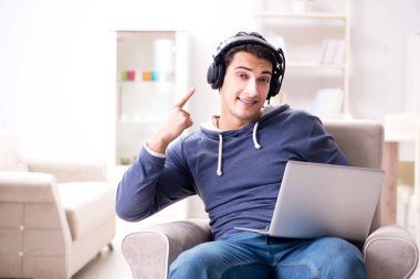 Genç yakışıklı adam kulaklıkla müzik dinliyor.