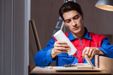 Genç adam ahşap parçaları DIY konseptinde yapıştırıyor.