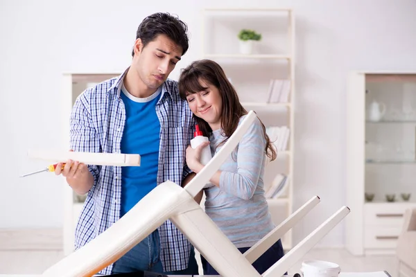 Ehefrau hilft Ehemann, kaputten Stuhl zu Hause zu reparieren — Stockfoto