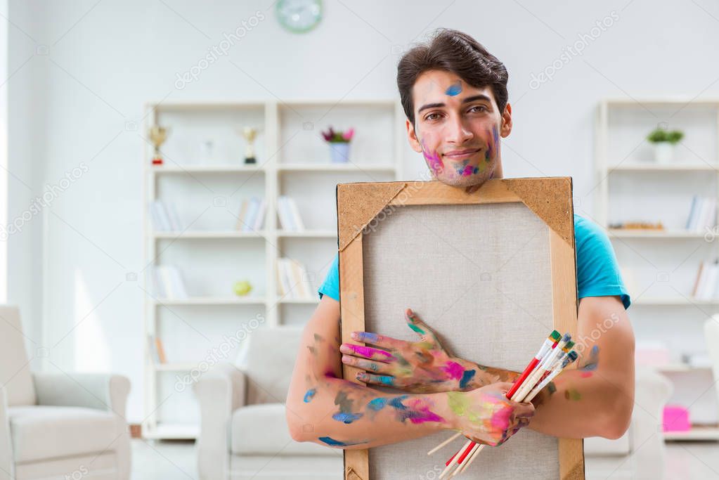 Young funny artist working on new painting in his studio