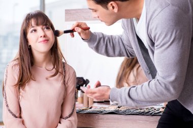 Güzellik salonunda güzel bir kadın için makyaj yapan adam.