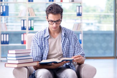 Öğrenci kitap okuyor ve kütüphanede sınavlara hazırlanıyor