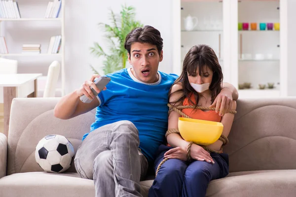 Мужчина связывает свою жену, чтобы смотреть спортивный футбол — стоковое фото