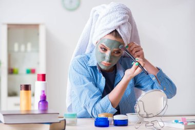 Kadın evde fırçayla kilden maske takıyor