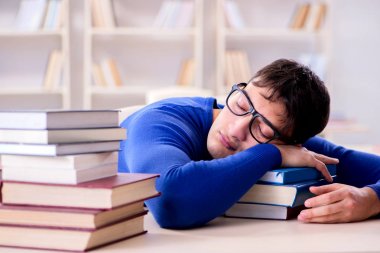 Erkek öğrenci üniversite kütüphanesinde sınava hazırlanıyor.