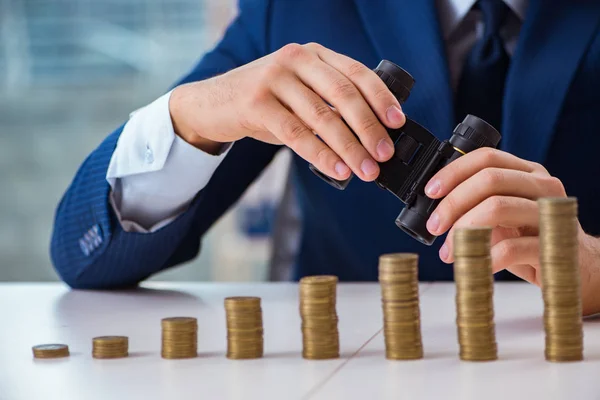 Empresario con pilas de monedas en la oficina — Foto de Stock