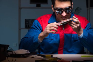 Bilgisayar uzmanı gece geç saatlerde bilgisayarı tamir ediyor.