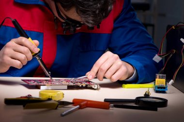 Bilgisayar uzmanı gece geç saatlerde bilgisayarı tamir ediyor.