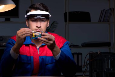 Bilgisayar uzmanı gece geç saatlerde bilgisayarı tamir ediyor.