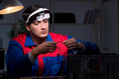 Bilgisayar uzmanı gece geç saatlerde bilgisayarı tamir ediyor.