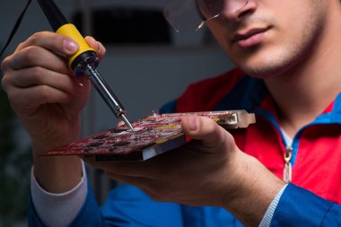 Bilgisayar uzmanı gece geç saatlerde bilgisayarı tamir ediyor.