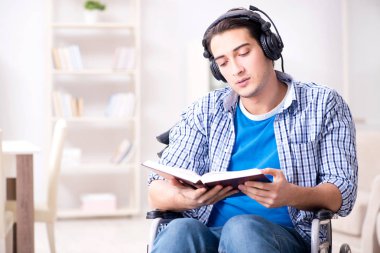 Tekerlekli sandalyede müzik dinleyen engelli adam.