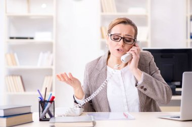 İş kadını çalışan ofis telefonundan konuşuyor.