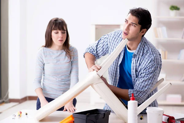 Moglie aiutare il marito a riparare sedia rotta a casa — Foto Stock