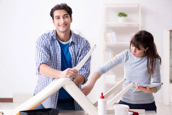 Żona pomaga mężowi naprawić zepsute krzesło w domu — Zdjęcie stockowe