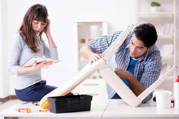 Ehefrau hilft Ehemann, kaputten Stuhl zu Hause zu reparieren — Stockfoto