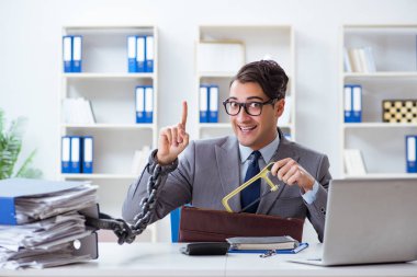 Ofis masasına zincirlenmiş meşgul bir çalışan.