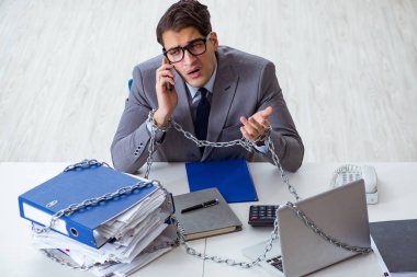 Ofis masasına zincirlenmiş meşgul bir çalışan.