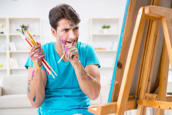 Молодой забавный художник работает над новой картиной в своей студии — стоковое фото