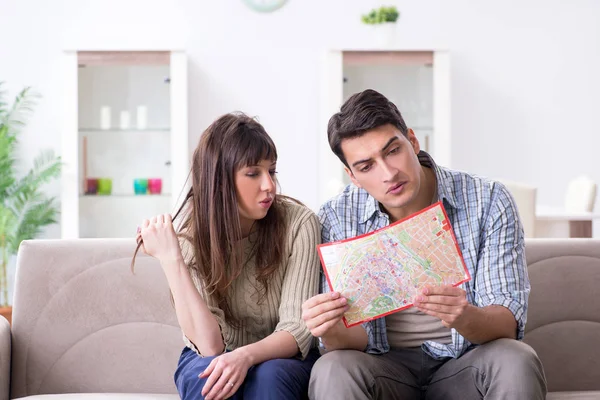 Ung familj diskuterar resplaner med karta — Stockfoto